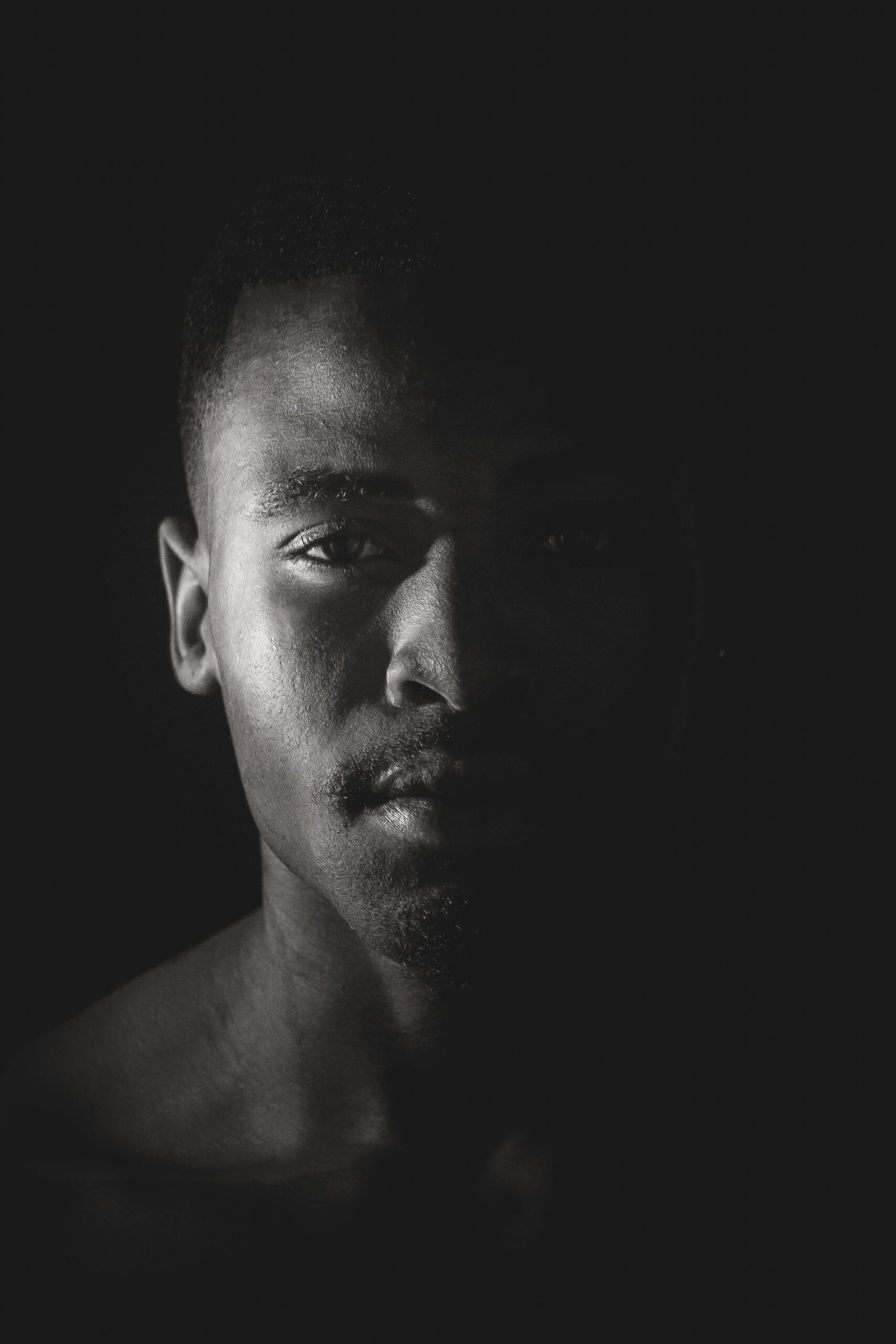Artistic black and white portrait of a man with dramatic lighting and expressive gaze.